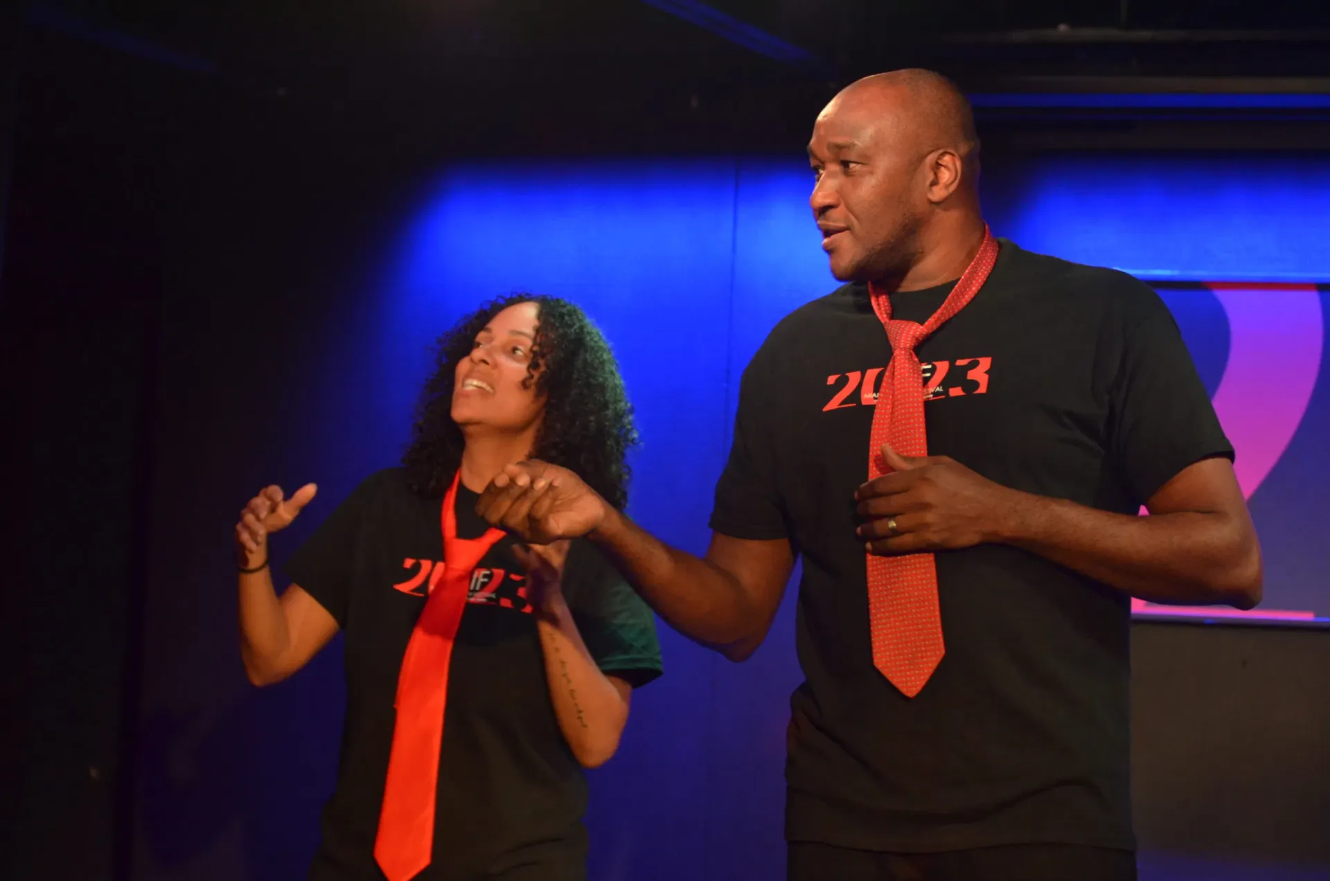 Two improvisers performing on stage under blue lights